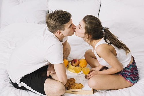 couple-kissing-bed-with-tray-food